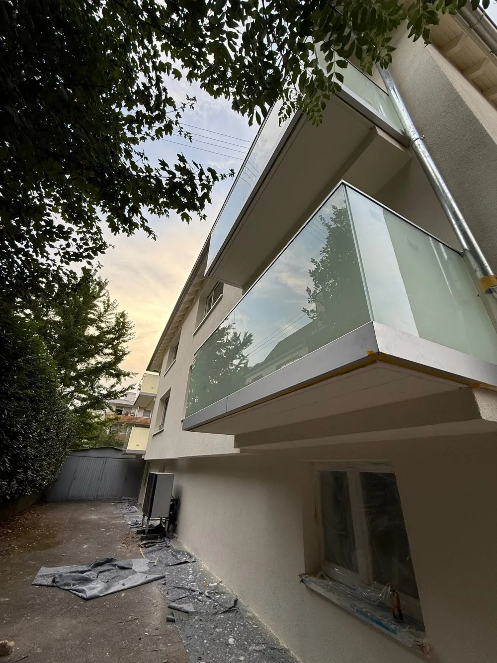 Modernisierter Balkon mit Glasbrüstung, heller Fassade, sauberer Balkonunterseite und gepflegter Außenansicht