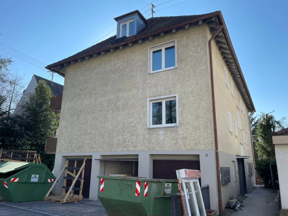 Mehrfamilienhaus vor der Fassadenmodernisierung mit alter Putzfassade, Baustellenbereich und renovierungsbedürftiger Außenansicht