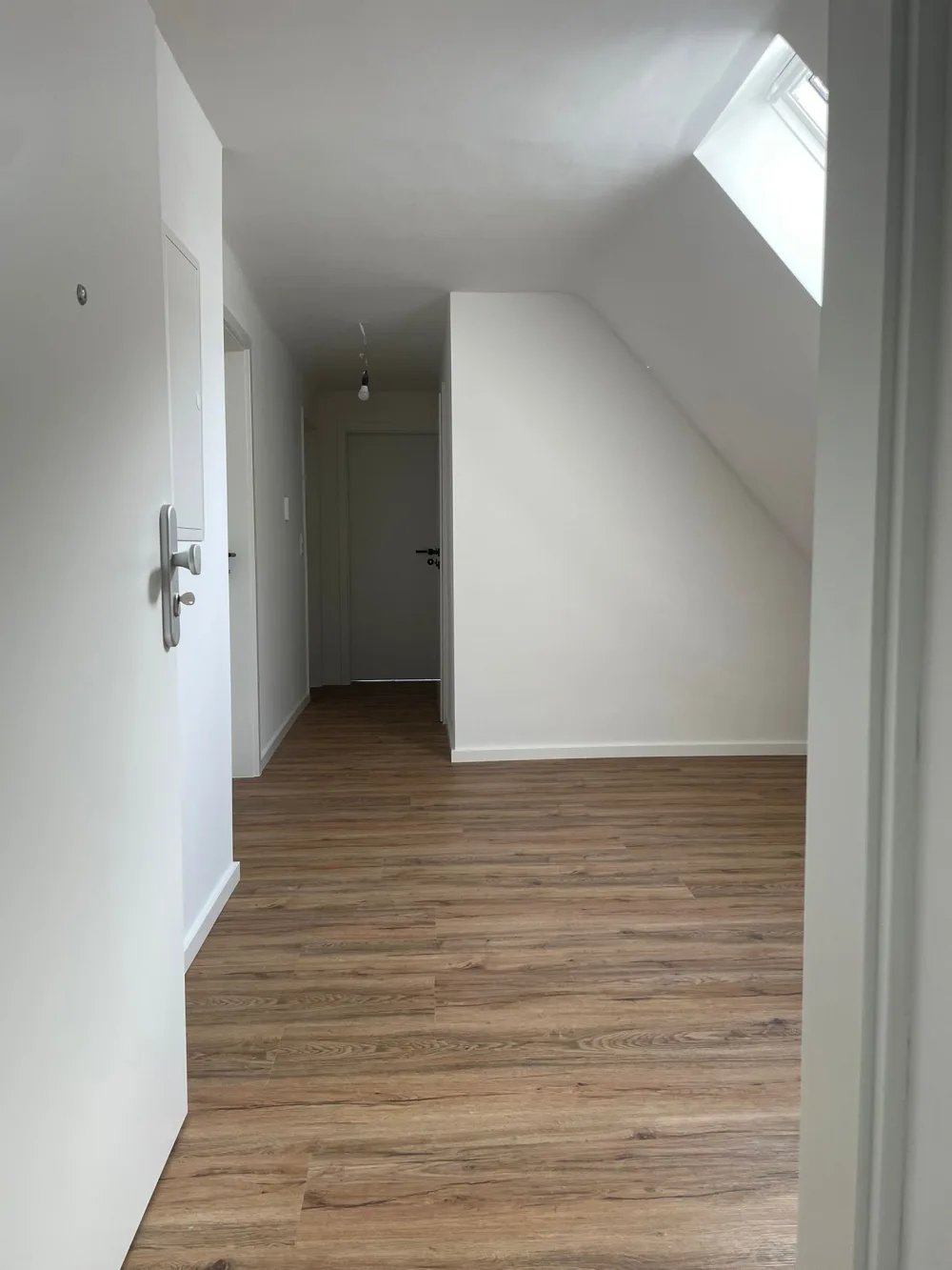 Modernisierter Dachgeschossbereich mit hellen Wänden, Holzoptik-Boden, Dachfenster, Türen und sauber ausgeführten Anschlüssen