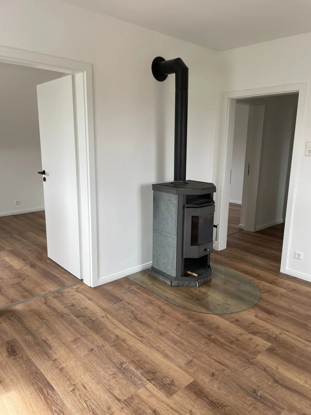 Modernisierter Wohnraum mit Kaminofen, weißen Wänden, neuen Türen, sauberen Zargen und Holzoptik-Boden