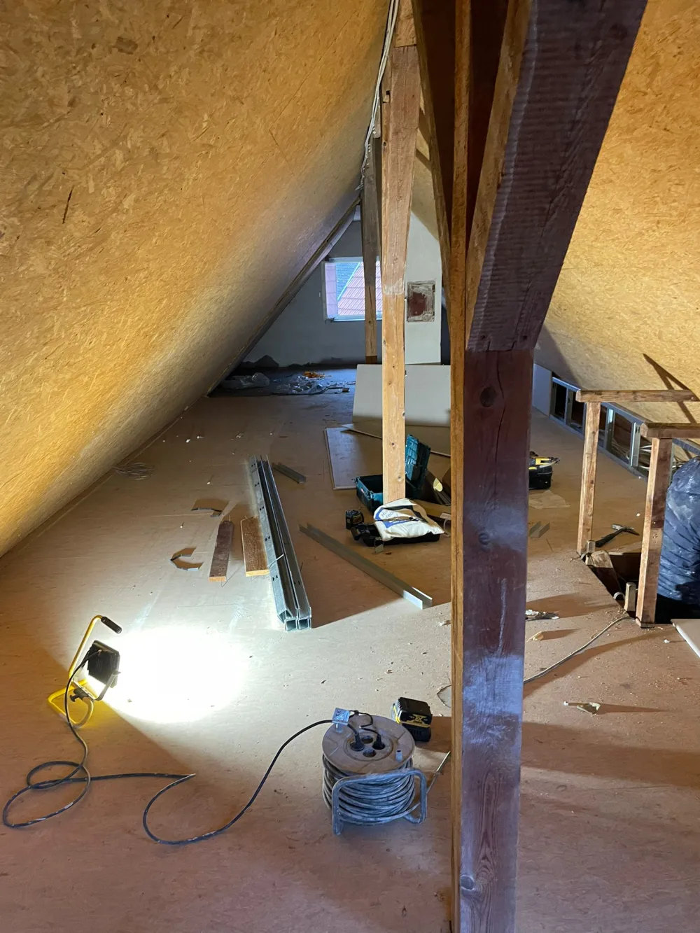 Dachgeschoss vor der Modernisierung mit OSB-Flächen, Rohboden, sichtbarer Holzkonstruktion und Baustellenmaterial